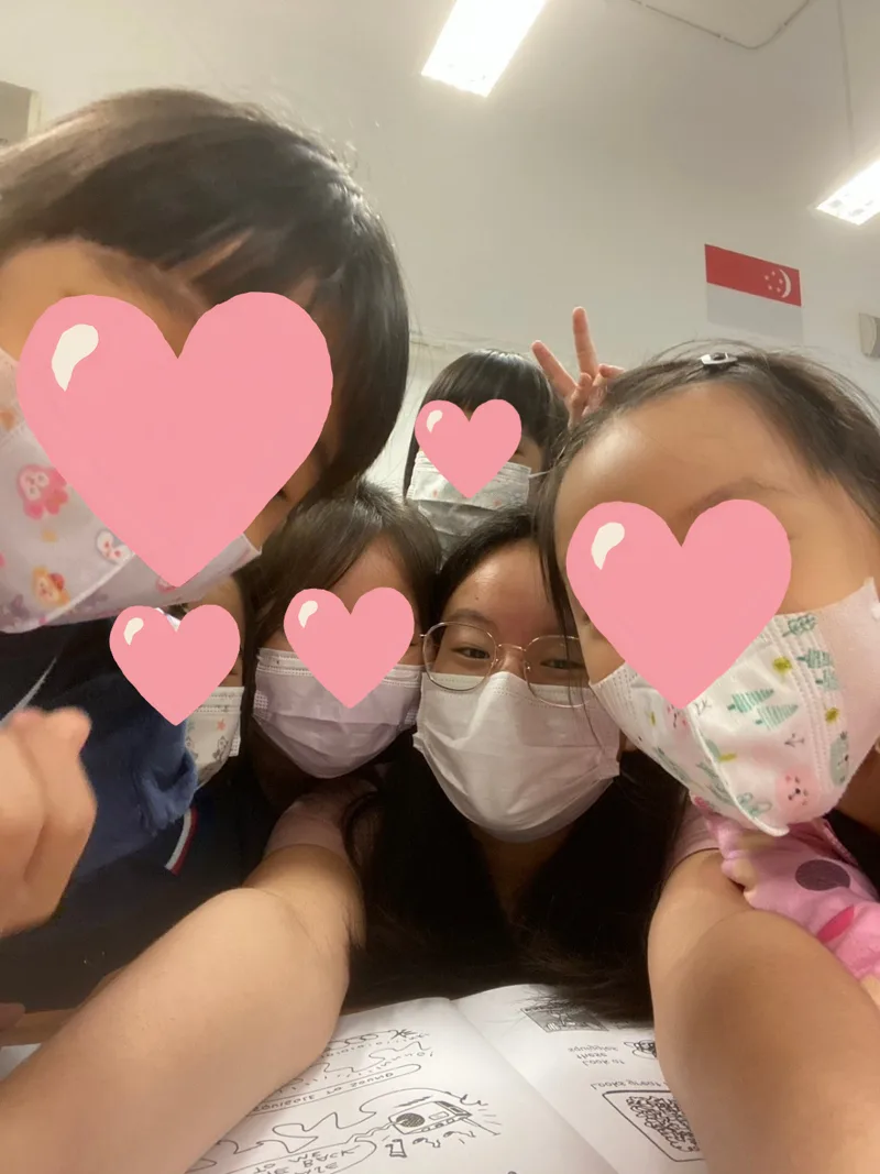 Teresa taking a selfie with her students, who have hearts drawn over their faces